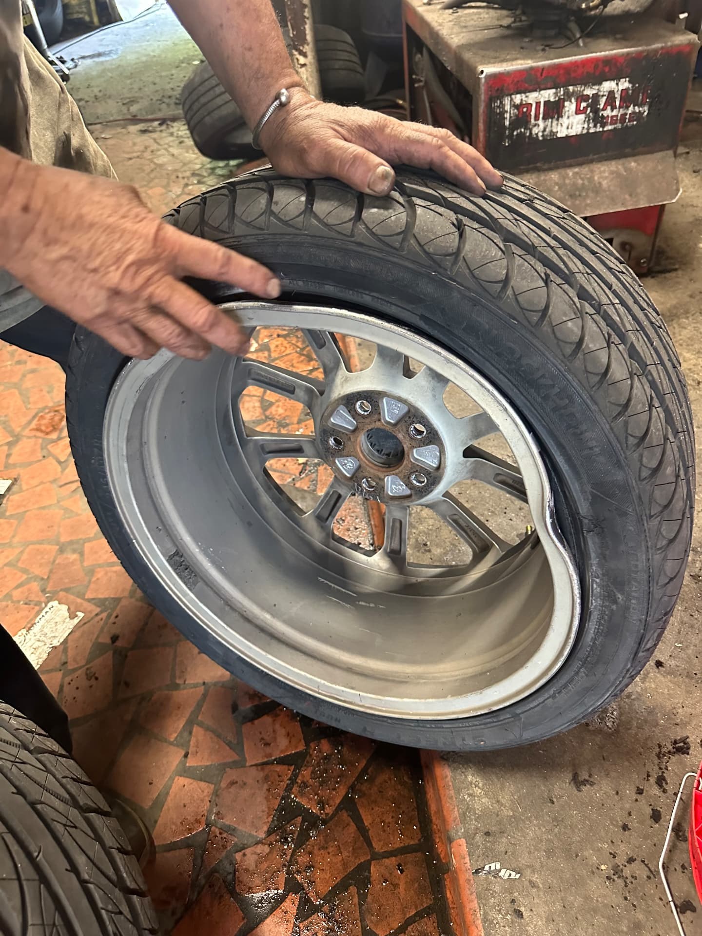 Technician examining a damaged alloy wheel rim before repair