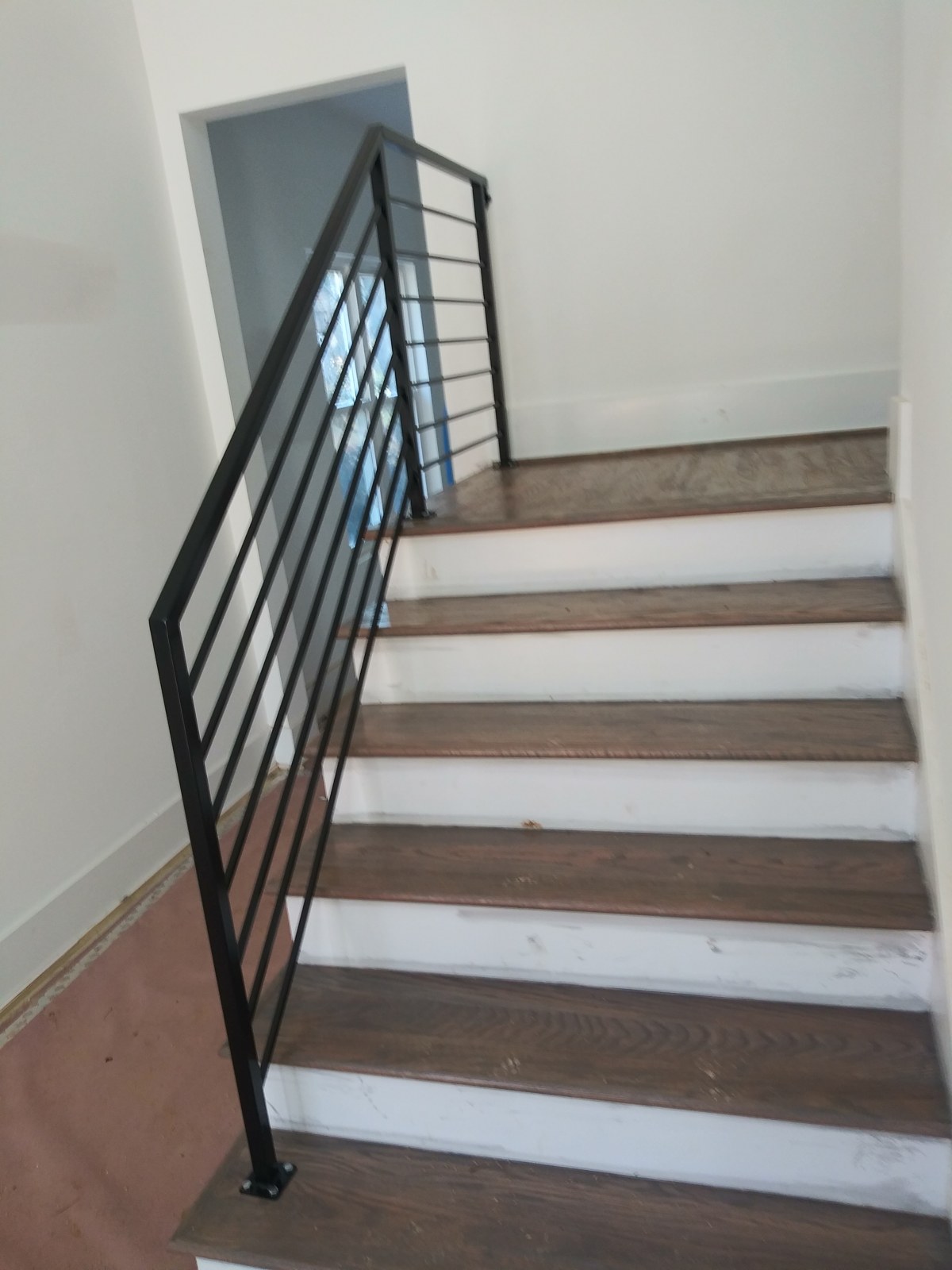 Black horizontal metal stair railing beside an interior staircase