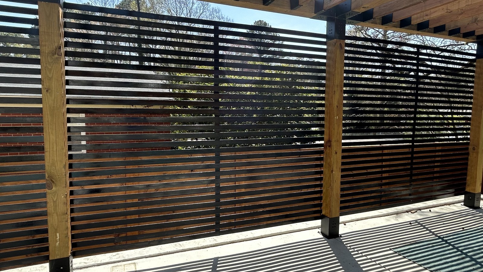 Horizontal metal privacy screen along a covered poolside patio