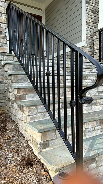 Black metal stair railing beside stone entry steps
