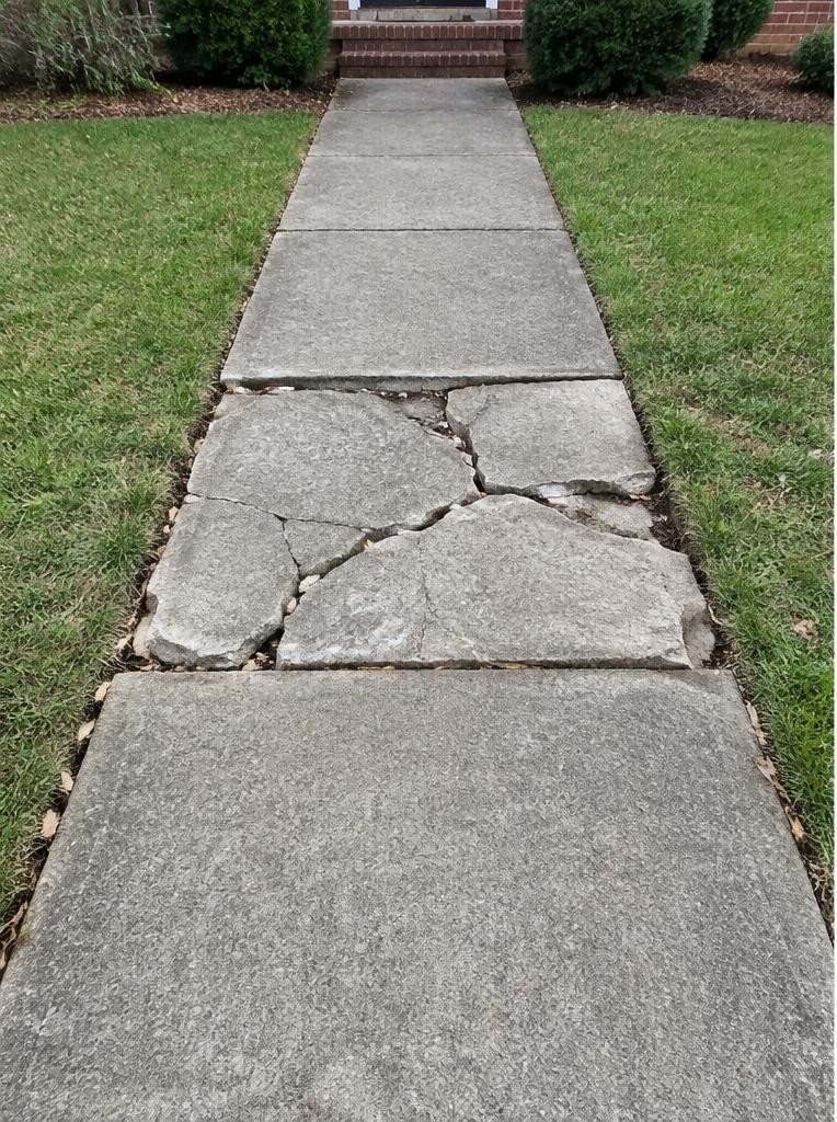 Broken and uneven concrete sidewalk panel before repair